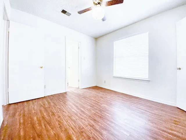 an empty room with wooden floor and windows