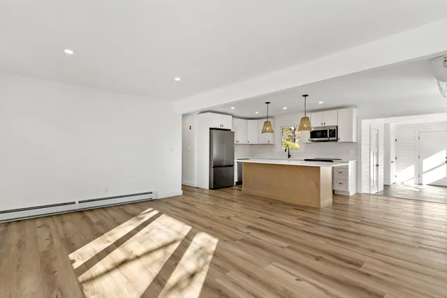 a view of a big room with wooden floor and windows