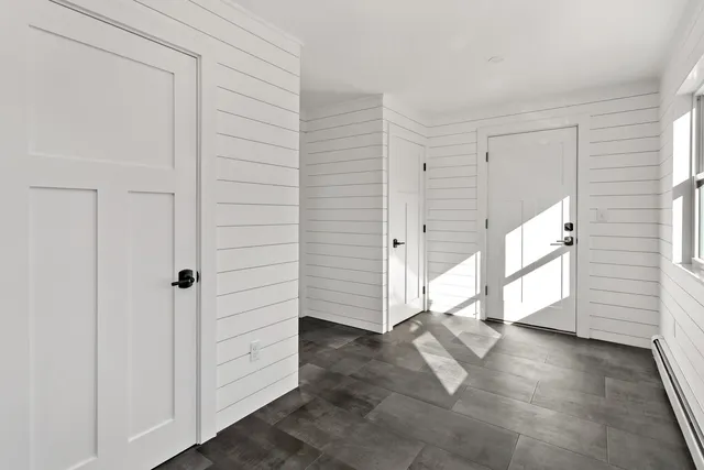 a view of an empty room with window and wooden floor