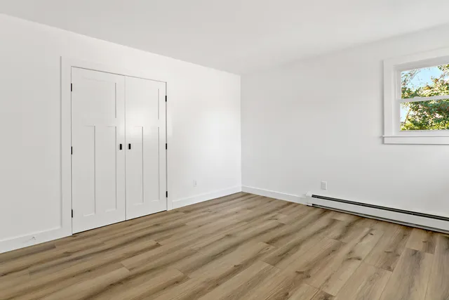 an empty room with wooden floor and window