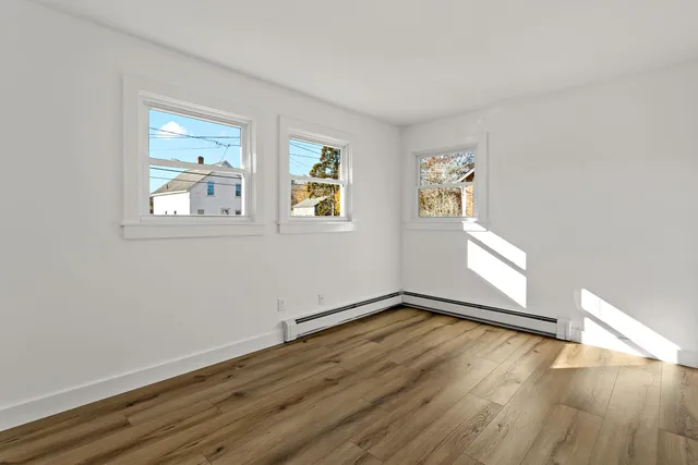 a view of an empty room with wooden floor and closet