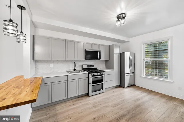 a kitchen with stainless steel appliances granite countertop a stove top oven a refrigerator a sink and dishwasher with wooden floor