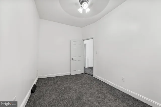 an empty room with a chandelier fan and a window