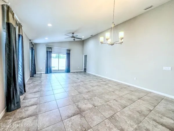 a view of a livingroom with a chandelier fan and windows