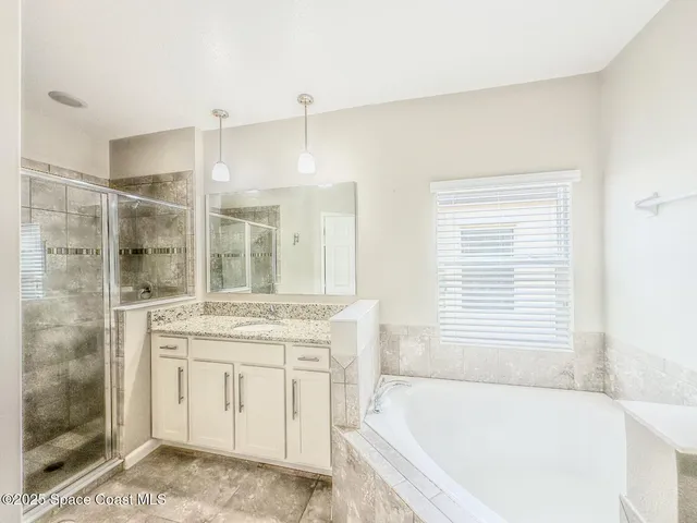 a bathroom with a granite countertop bathtub a sink and a shower