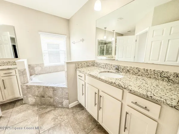 a bathroom with a granite countertop sink a mirror and a bathtub