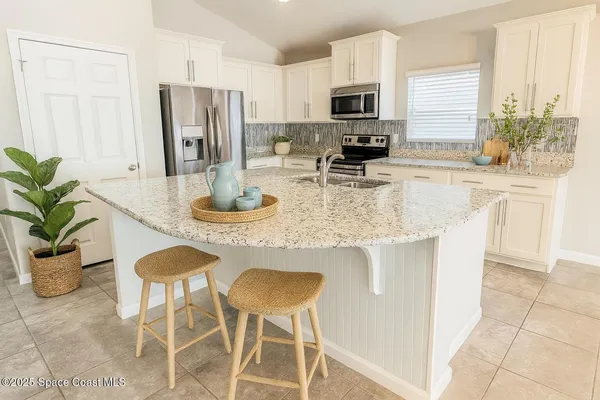 a kitchen with stainless steel appliances granite countertop a stove a refrigerator a sink a dining table and chairs with wooden floor