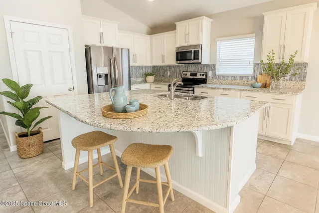 a kitchen with stainless steel appliances granite countertop a stove a refrigerator a sink a dining table and chairs with wooden floor