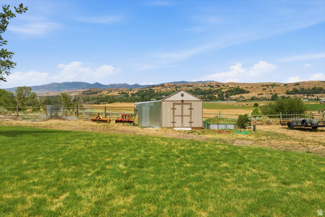 3123 East Riverdale Road Preston, ID 83263 - Photo 37 of 52 Expansive grassy yard with mountain scenery, featuring a storage shed and perimeter fencing
