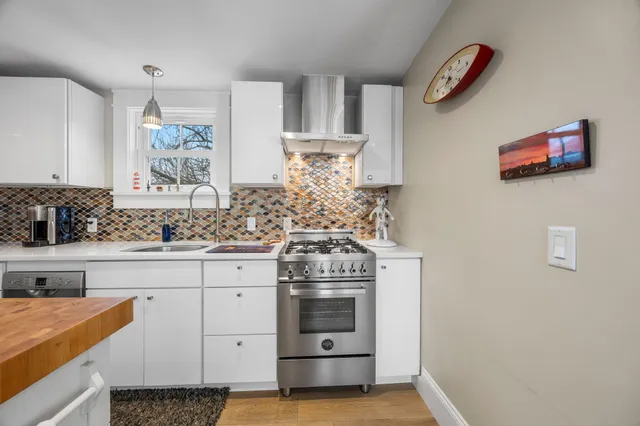 a kitchen with stainless steel appliances a stove and white cabinets