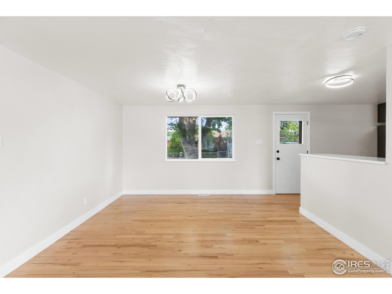 1245 Sumner Street Longmont, CO 80501 - Photo 11 of 25 an empty room with wooden floor and windows