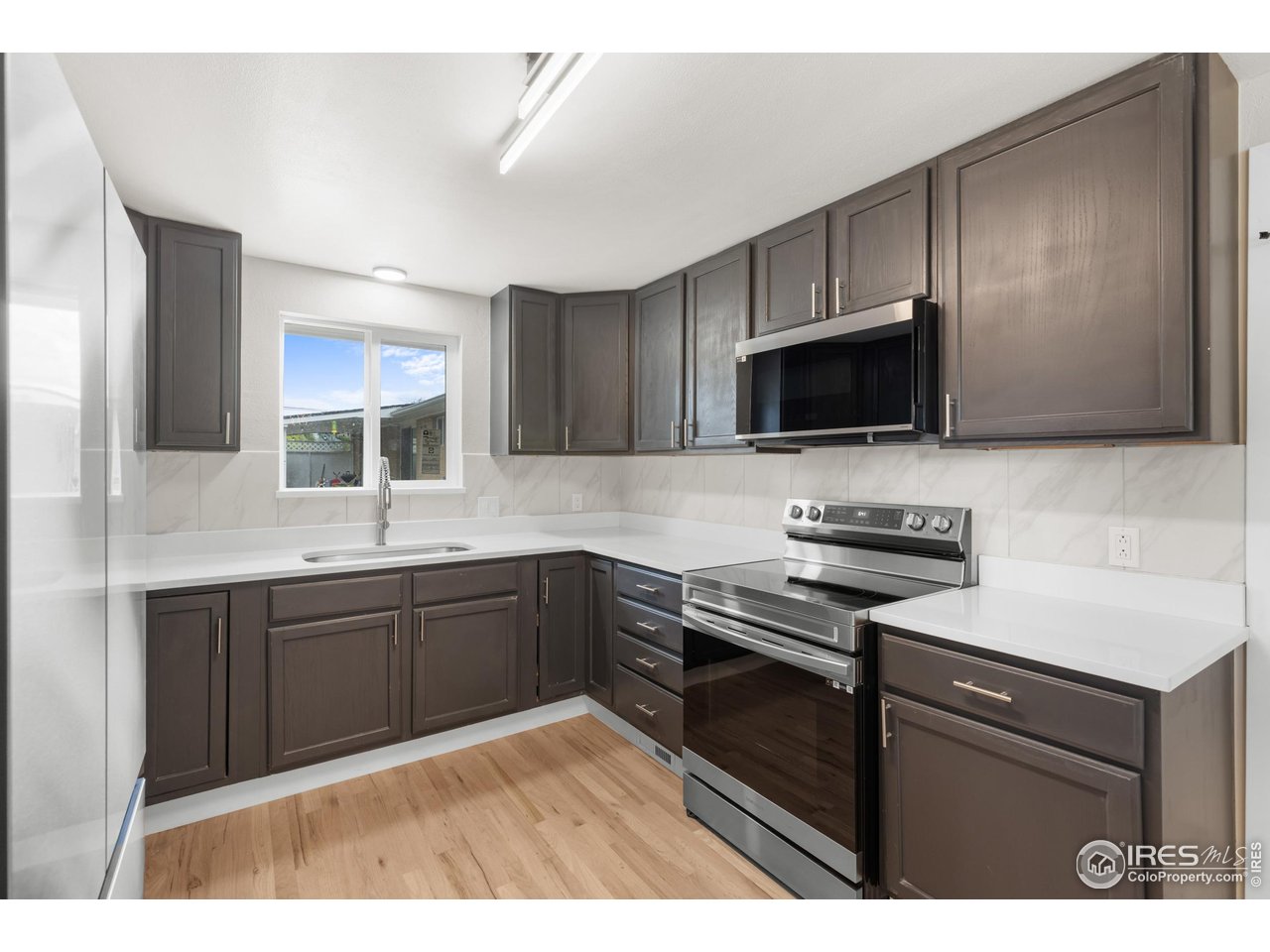 1245 Sumner Street Longmont, CO 80501 - Photo 12 of 25 a kitchen with stainless steel appliances a stove sink microwave and cabinets