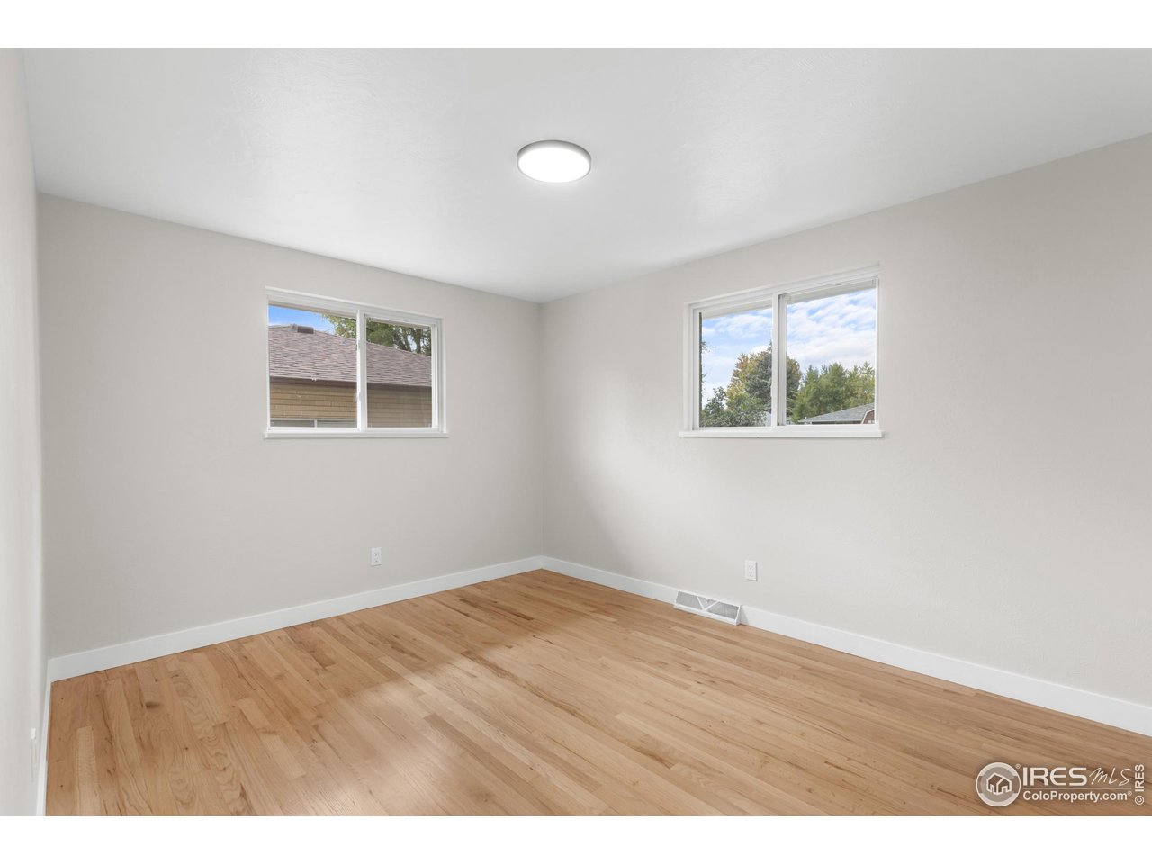 1245 Sumner Street Longmont, CO 80501 - Photo 15 of 25 an empty room with wooden floor and windows