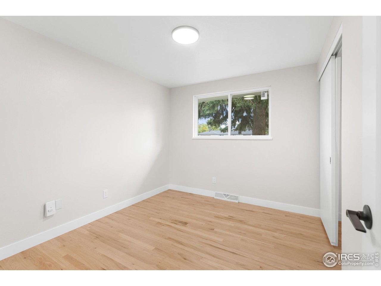 1245 Sumner Street Longmont, CO 80501 - Photo 17 of 25 a view of an empty room with wooden floor and a window