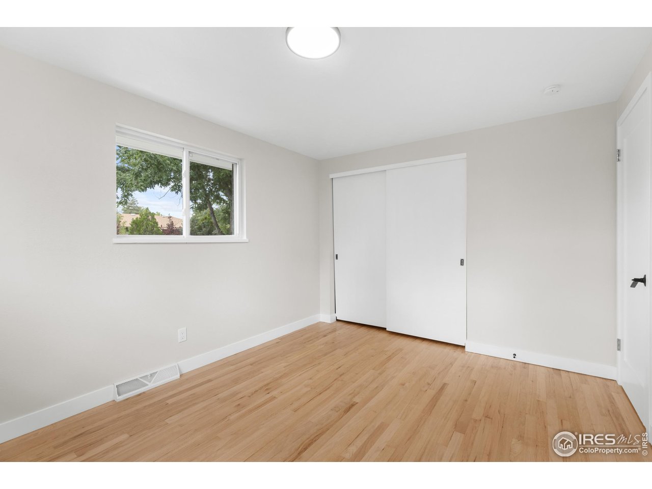 1245 Sumner Street Longmont, CO 80501 - Photo 18 of 25 an empty room with wooden floor and windows