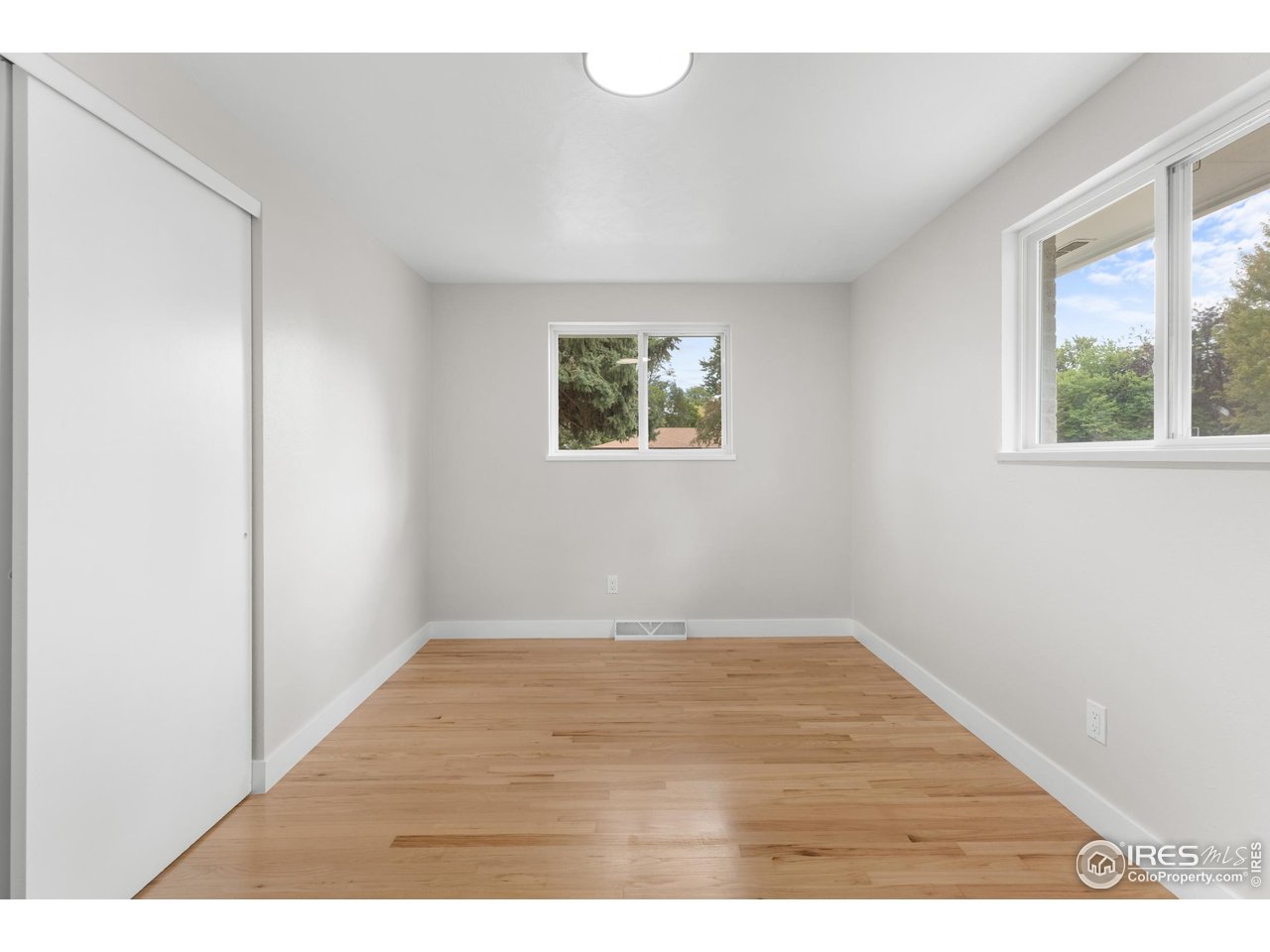 1245 Sumner Street Longmont, CO 80501 - Photo 19 of 25 an empty room with wooden floor and windows