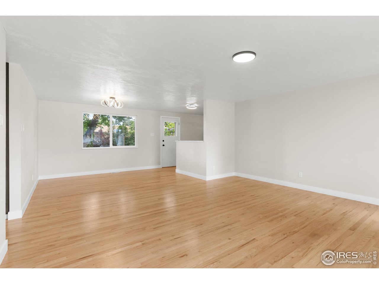 1245 Sumner Street Longmont, CO 80501 - Photo 8 of 25 a view of an empty room with wooden floor and a window