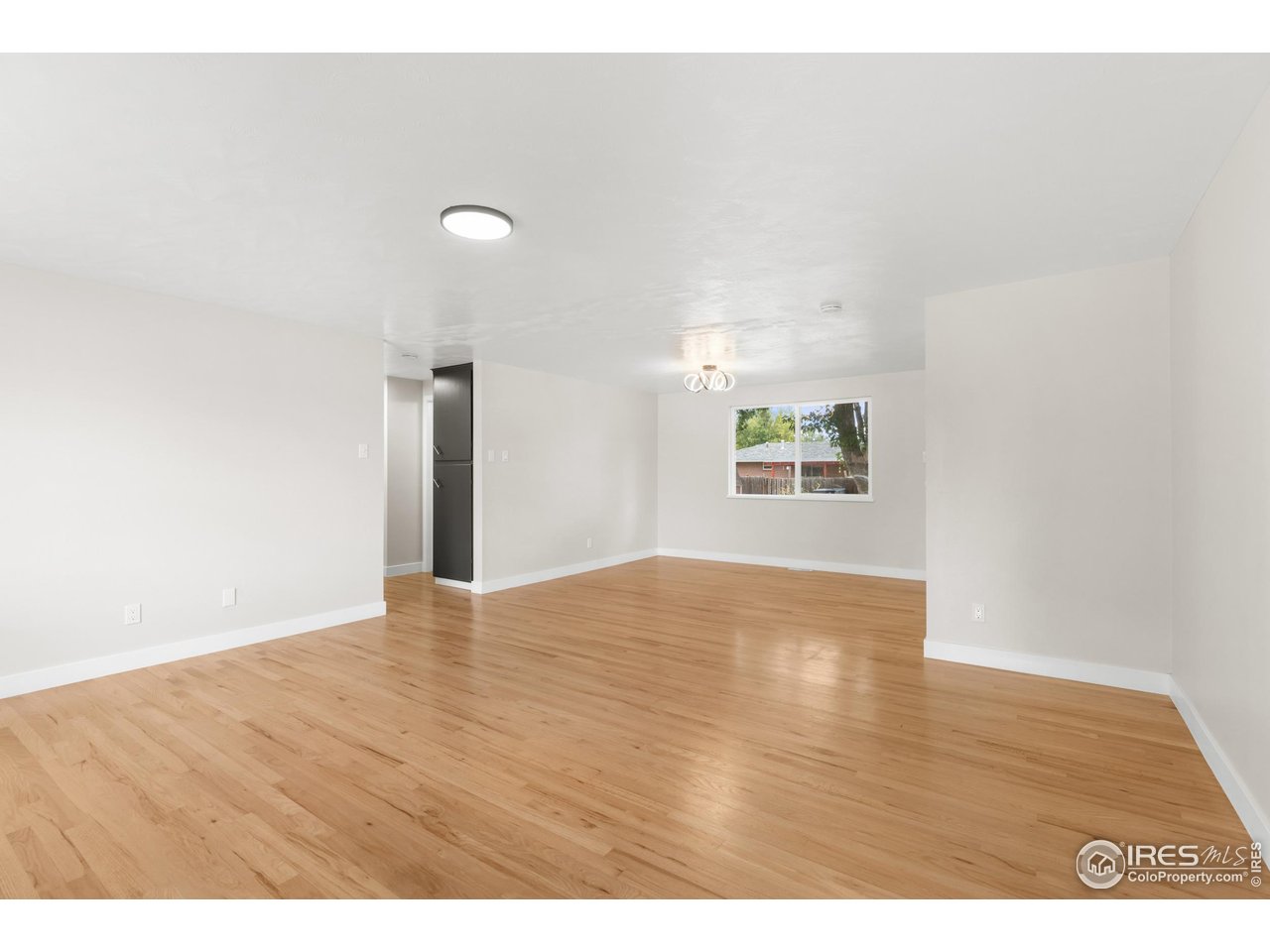1245 Sumner Street Longmont, CO 80501 - Photo 9 of 25 a view of an empty room with wooden floor and a window
