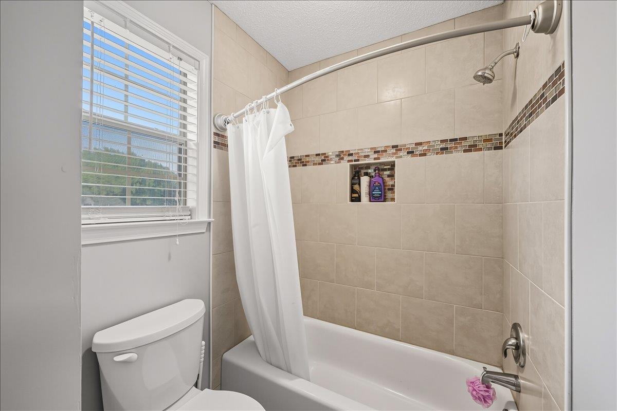 6870 Deerfield Road Bartlett, TN 38135 - Photo 18 of 28 Bathroom with shower / bath combination with curtain and a textured ceiling