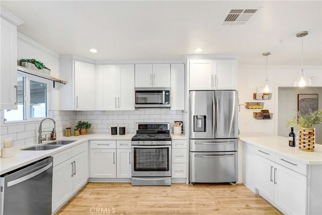 a kitchen with white cabinets and stainless steel appliances