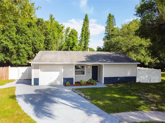 a front view of house with yard and trees in the background