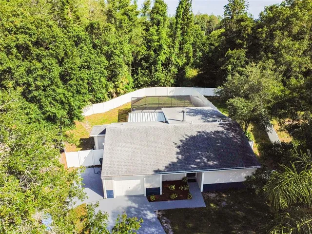 an aerial view of a house with yard and swimming pool