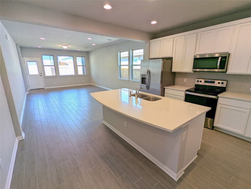 121 Drifter Lane Jarrell, TX 76537 - Photo 3 of 17 a kitchen with stainless steel appliances a microwave a sink a stove a microwave a refrigerator white cabinets and wooden floor