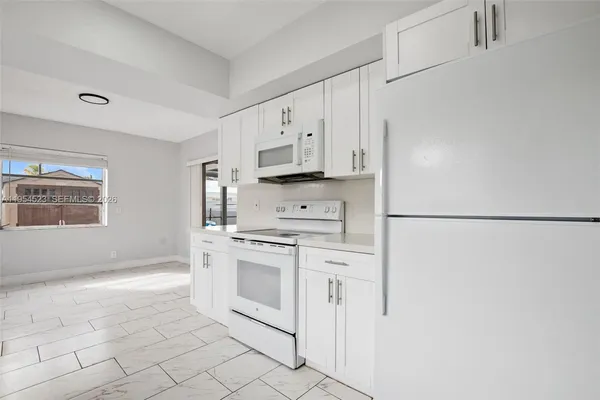 a large white kitchen with cabinets and wooden floor