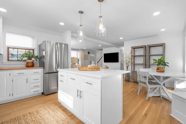 a large white kitchen with lots of counter space and stainless steel appliances