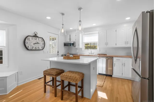 a kitchen with cabinets a center island stainless steel appliances and a window