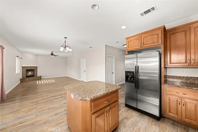 a kitchen with stainless steel appliances granite countertop a refrigerator a stove and a sink with wooden floor