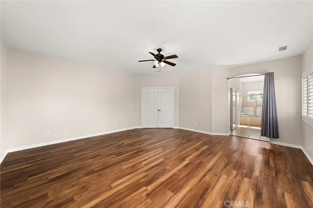 an empty room with wooden floor and ceiling fan