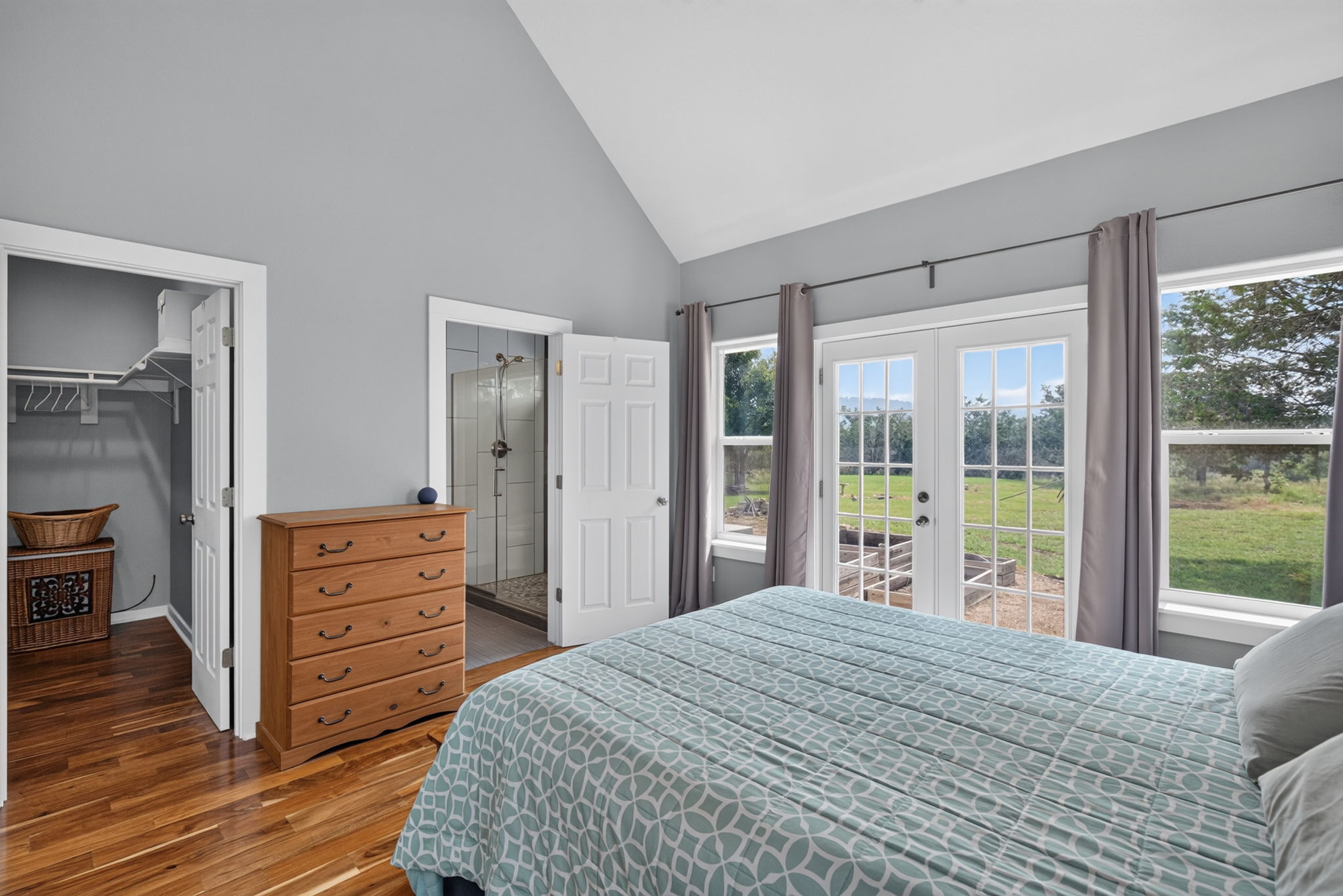 207 Deer Ridge Drive Burnet, TX 78611 - Photo 24 of 36 An airy primary bedroom with soaring vaulted ceilings and rich hardwood flooring offers direct outdoor access through elegant French doors.