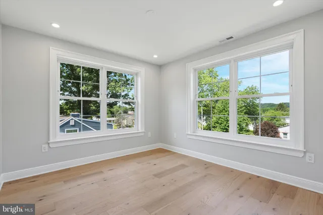 a view of an empty room with wooden floor and windows
