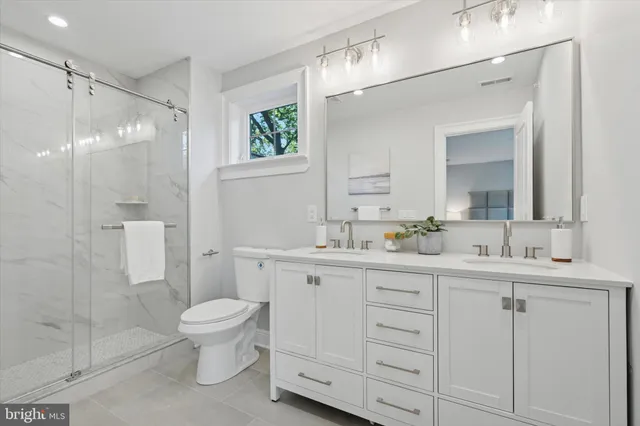 a bathroom with a toilet a sink a glass door a shower a mirror a vanity and