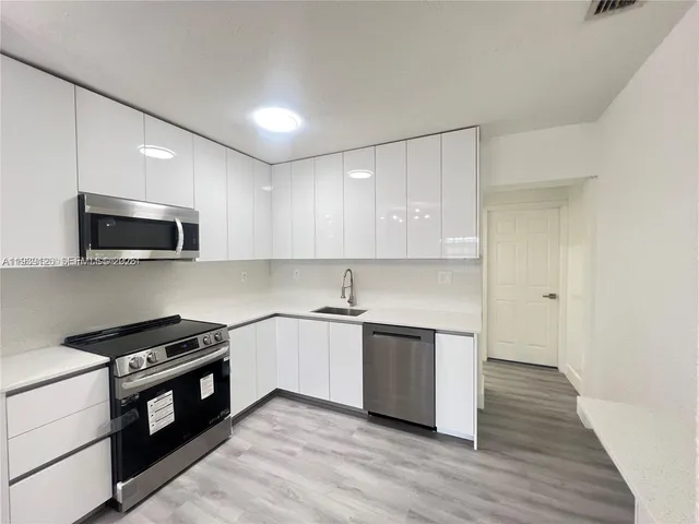 a kitchen with granite countertop a sink and steel appliances