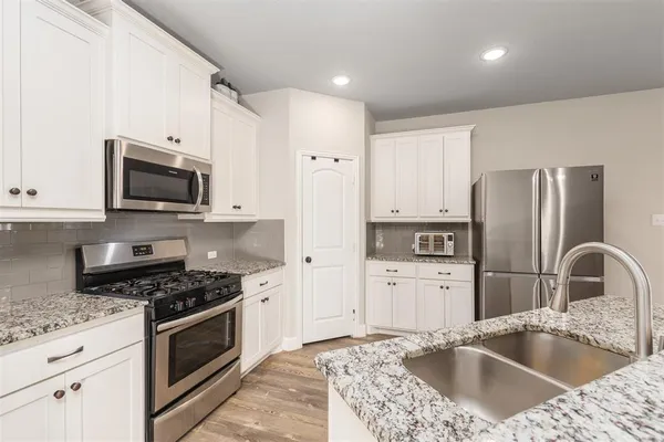 a kitchen with granite countertop a refrigerator stove and sink