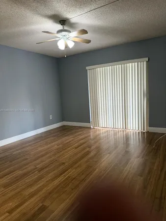an empty room with wooden floor fan and windows
