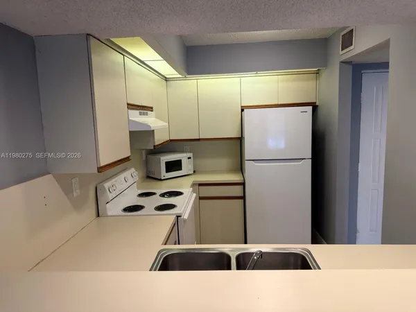 a kitchen with stainless steel appliances kitchen island a refrigerator sink and cabinets