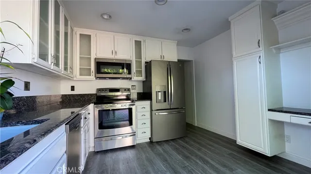 a kitchen with granite countertop a refrigerator stove and sink