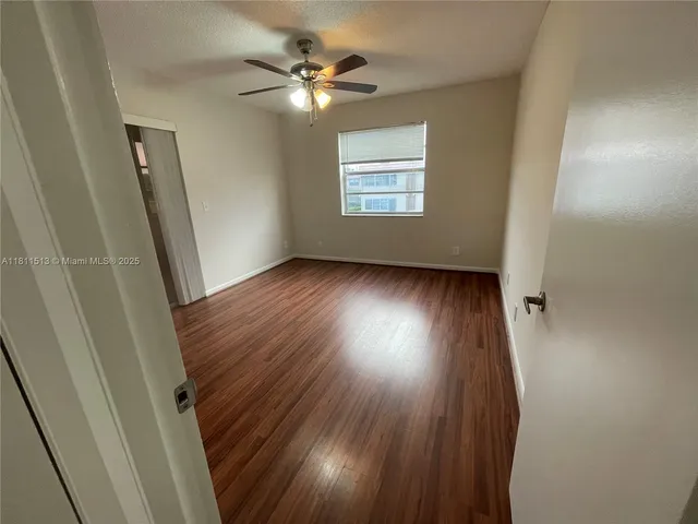 an empty room with wooden floor fan and windows