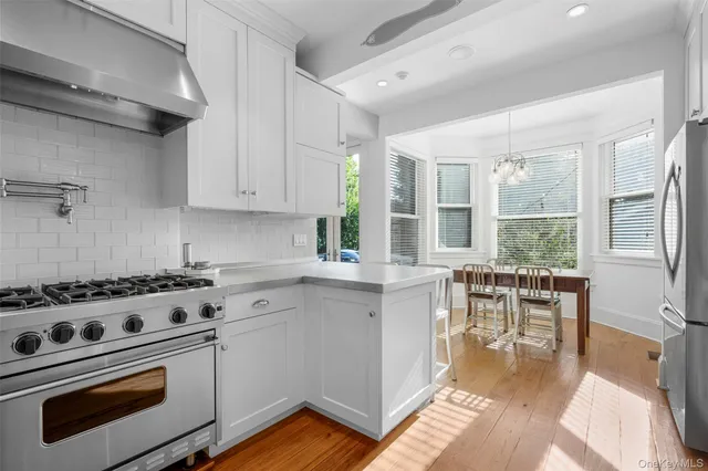 a kitchen with a stove a sink dishwasher a dining table and chairs with wooden floor