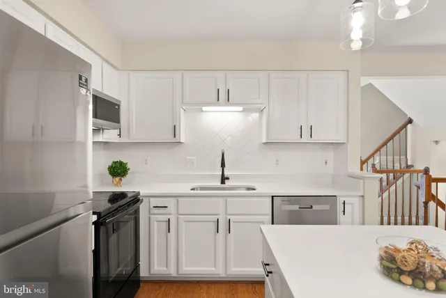 a kitchen with kitchen island granite countertop a sink a stove and cabinets