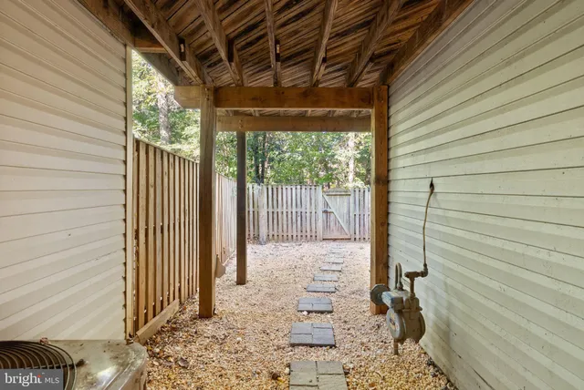 a backyard of a house with large trees and wooden fence