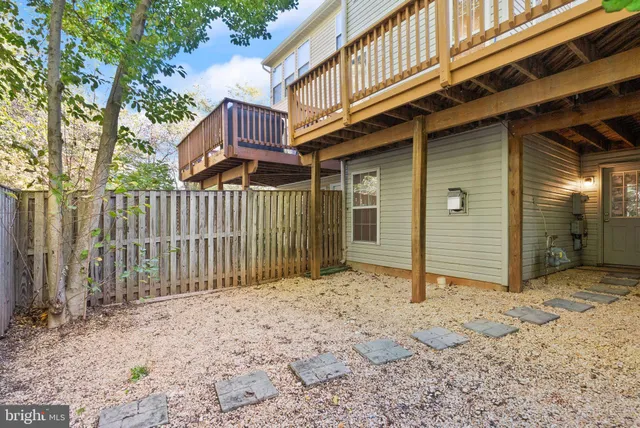 a view of a house with wooden fence and large trees