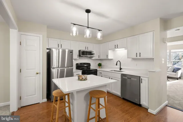 a kitchen with stainless steel appliances a dining table a sink a stove and refrigerator