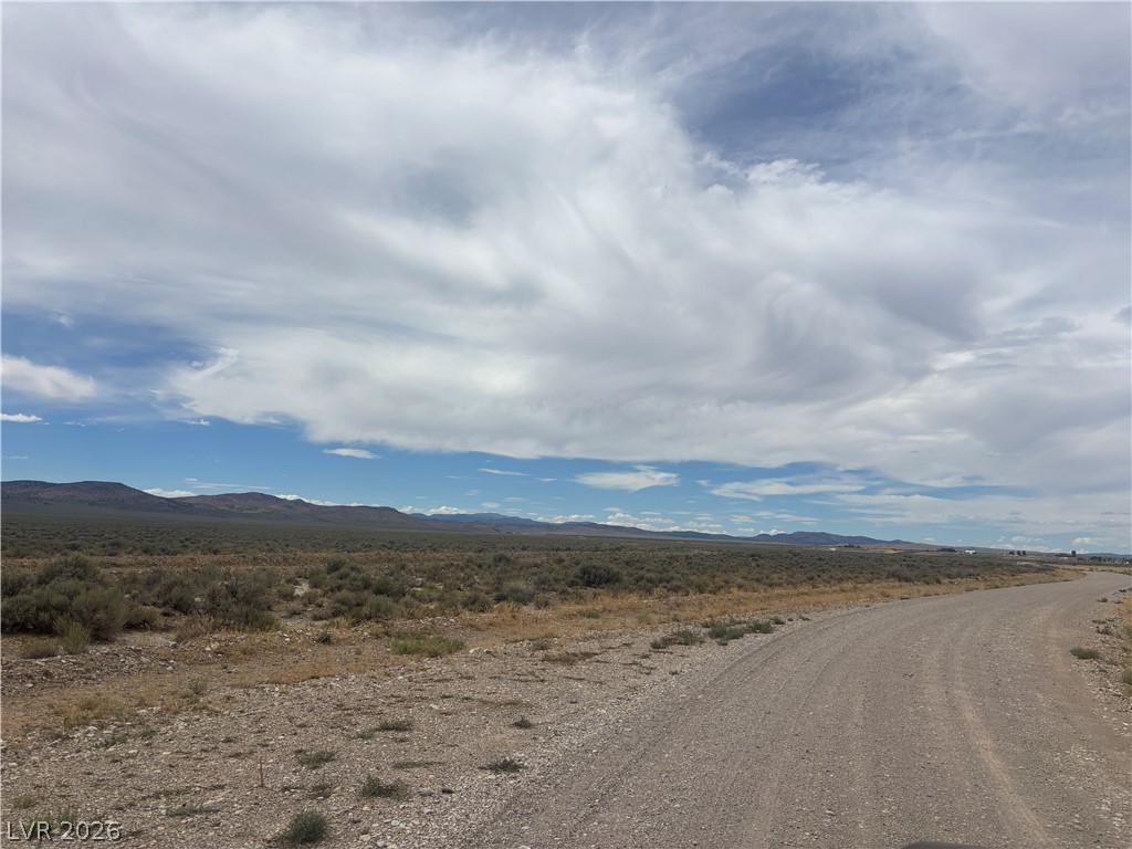 Preston Dump Road Lund, NV 89317 - Photo 5 of 7 A sweeping dirt road curves through the vast desert landscape toward distant mountain ranges.