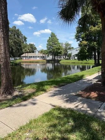 a view of a lake with a yard and a large tree