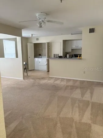 a view of living room with kitchen island stainless steel appliances cabinets and a window