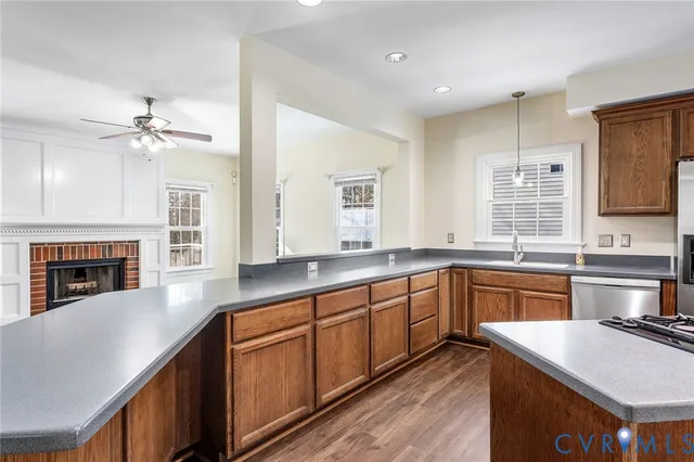 a kitchen with stainless steel appliances granite countertop a refrigerator a sink dishwasher and a stove with wooden floors